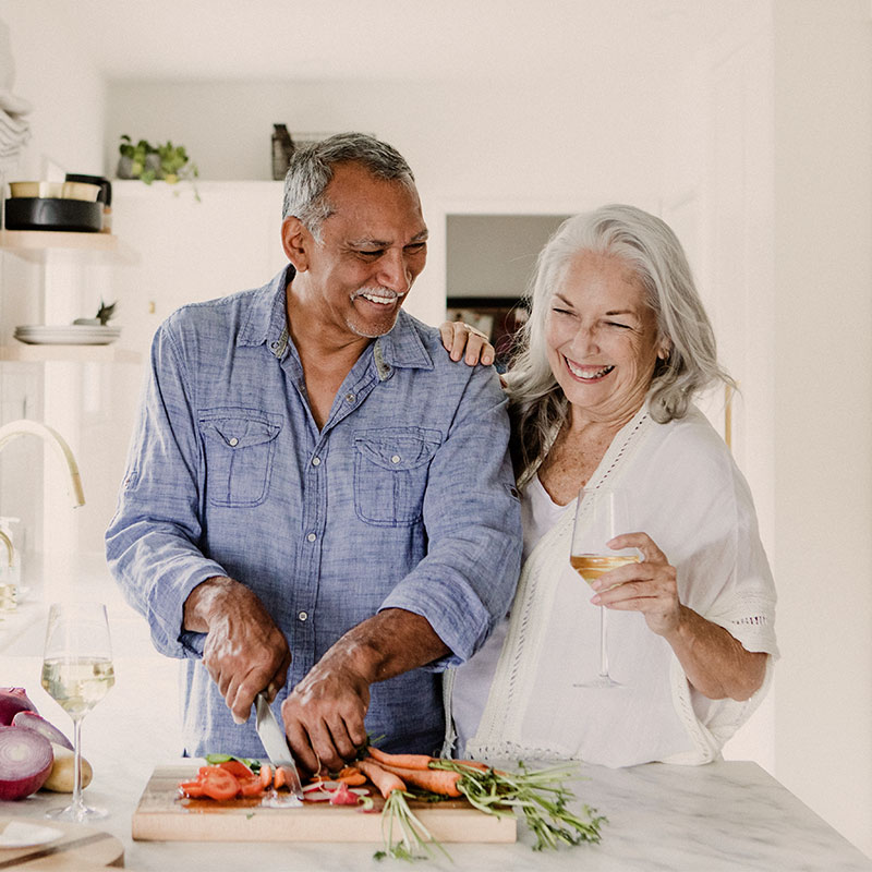 smiling senior couple making dinner at the kitchen island successful retirement